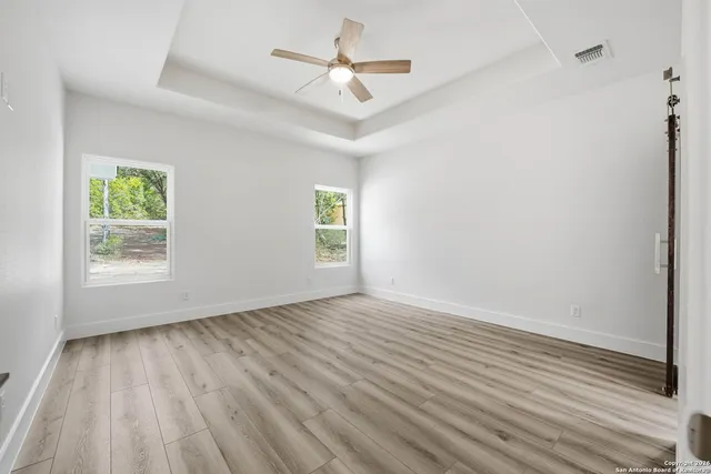 an empty room with wooden floor and a ceiling fan