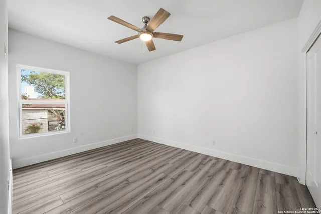 a view of an empty room with a window and wooden floor