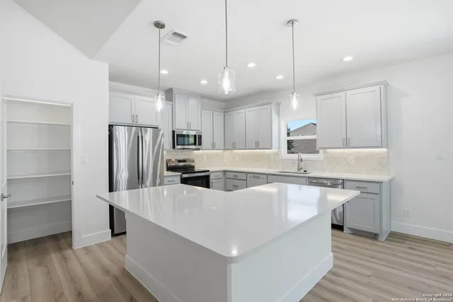 a large kitchen with kitchen island a stove a sink a center island and a wooden floor