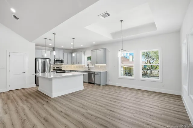a large kitchen with white cabinets a sink a window and stainless steel appliances