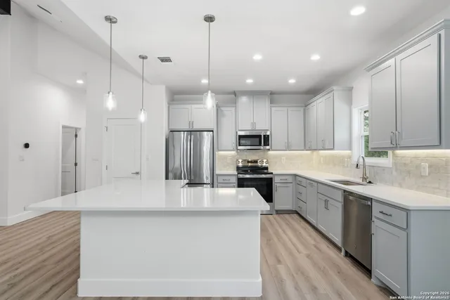 a large kitchen with kitchen island a sink stainless steel appliances and cabinets