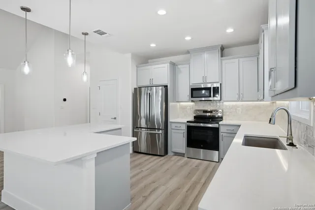a kitchen with a refrigerator a sink a stove and cabinets