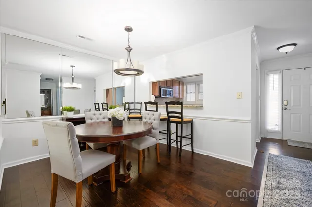 a view of a dining room and livingroom with furniture wooden floor a chandelier