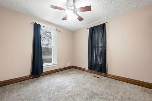 an empty room with windows and fan