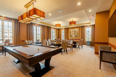 a room with furniture pool table and large windows