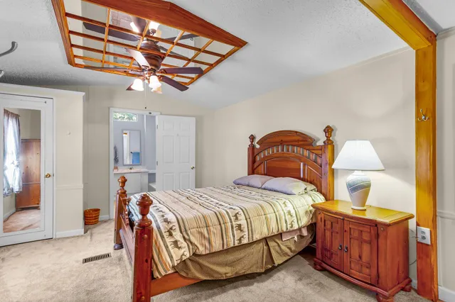 a bedroom with a bed a dresser and chandelier