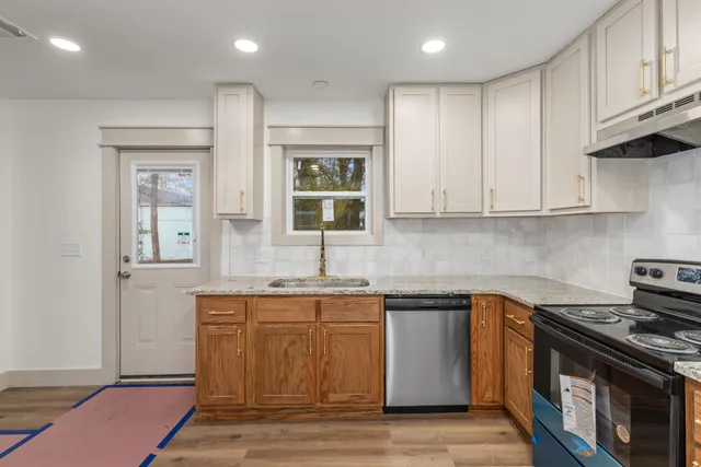 a kitchen with stainless steel appliances granite countertop a stove a sink and a microwave