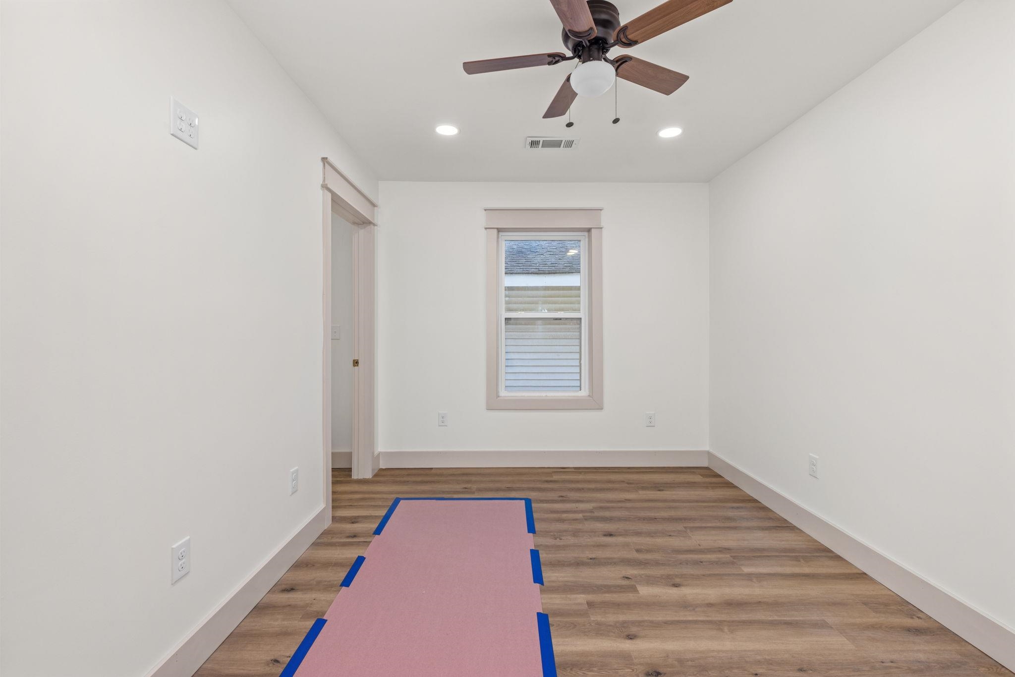 1008 North Madison Street Corinth, MS 38834 - Photo 8 of 33 an empty room with wooden floor fan and windows