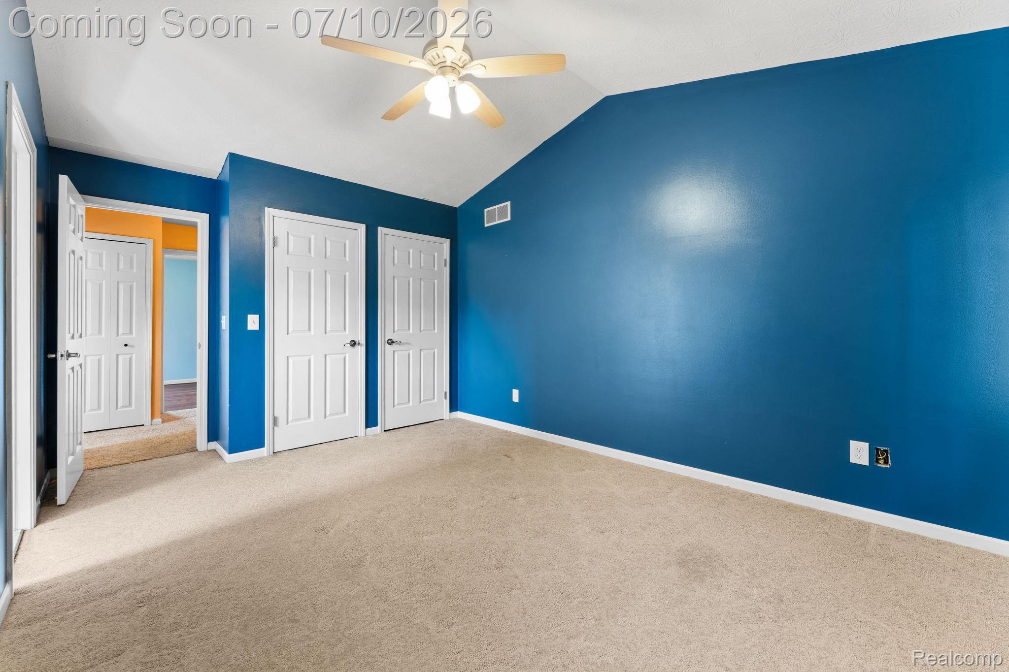 3144 North Nicholson Road Fowlerville, MI 48836 - Photo 54 of 70 Carpeted room featuring a vaulted ceiling with a ceiling fan, vibrant blue walls, and multiple paneled doors