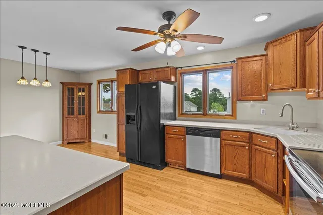 a kitchen with stainless steel appliances granite countertop a refrigerator a sink dishwasher a dining table and chairs with wooden floor