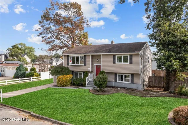 a front view of a house with a garden and trees