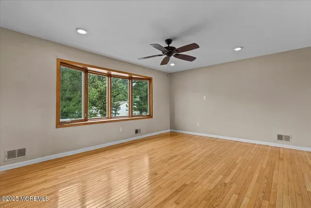 a view of an empty room with a window and a ceiling fan