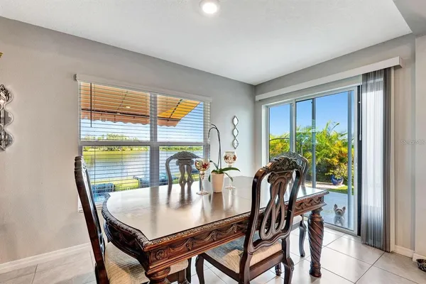 a dining room with furniture a potted plant and a large window