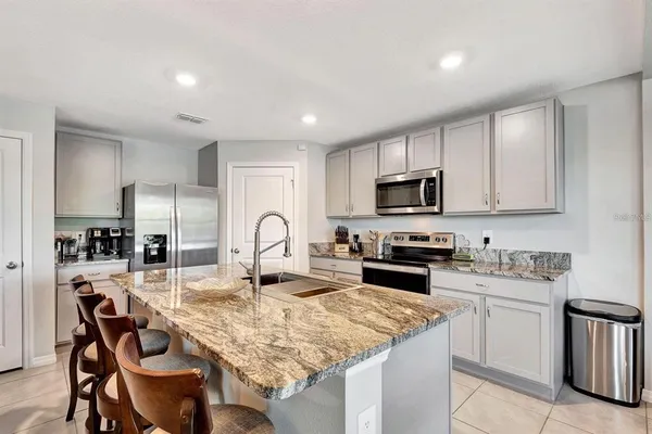 a kitchen with kitchen island granite countertop a table chairs microwave and cabinets