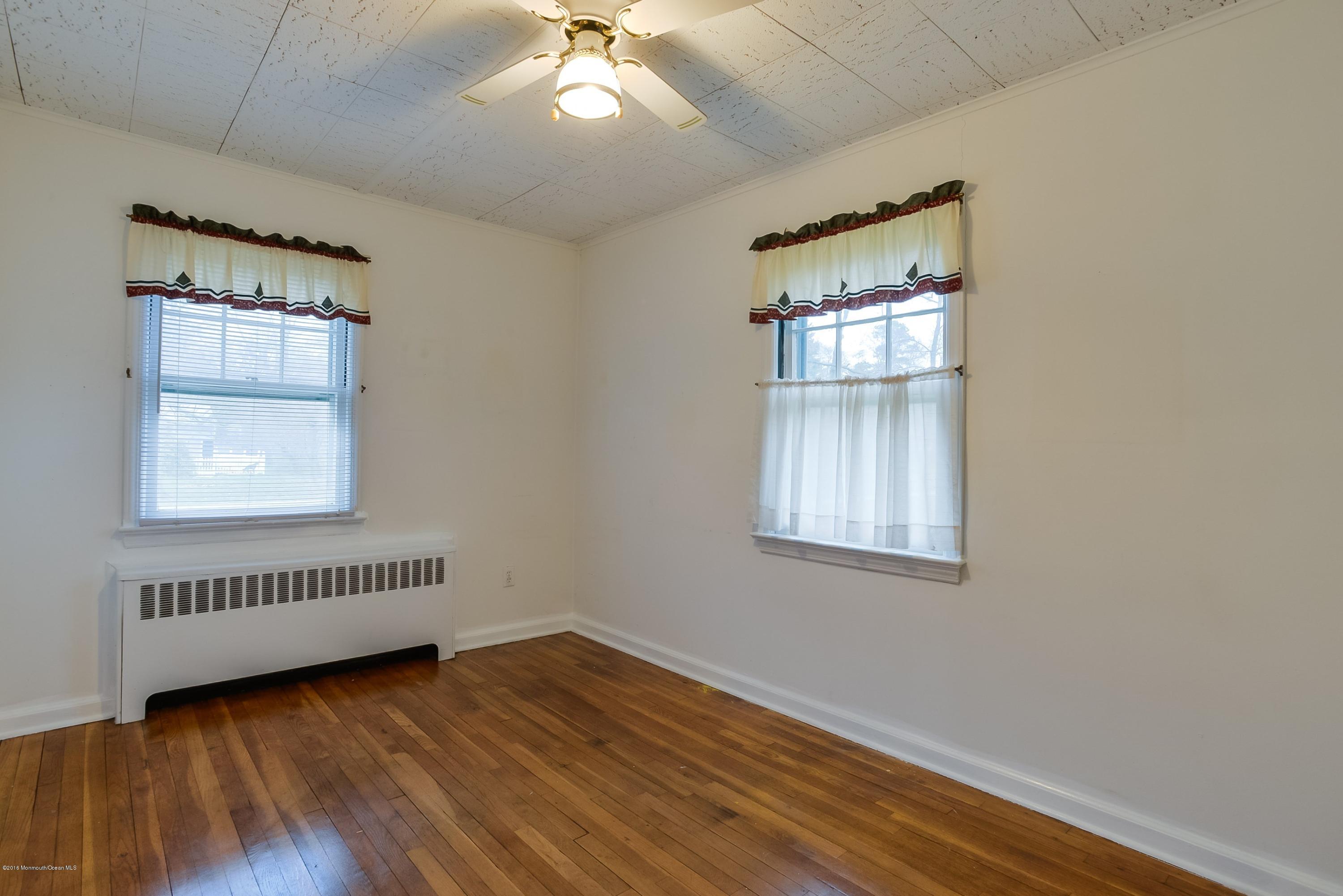 229 Pinecrest Road Oakhurst, NJ 07755 - Photo 7 of 12 an empty room with wooden floor chandelier and windows