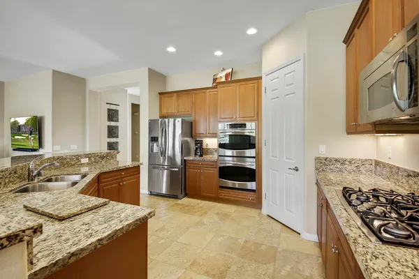 a kitchen with stainless steel appliances granite countertop a stove refrigerator and a sink