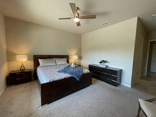 a bedroom with a bed and a lamp on the dresser