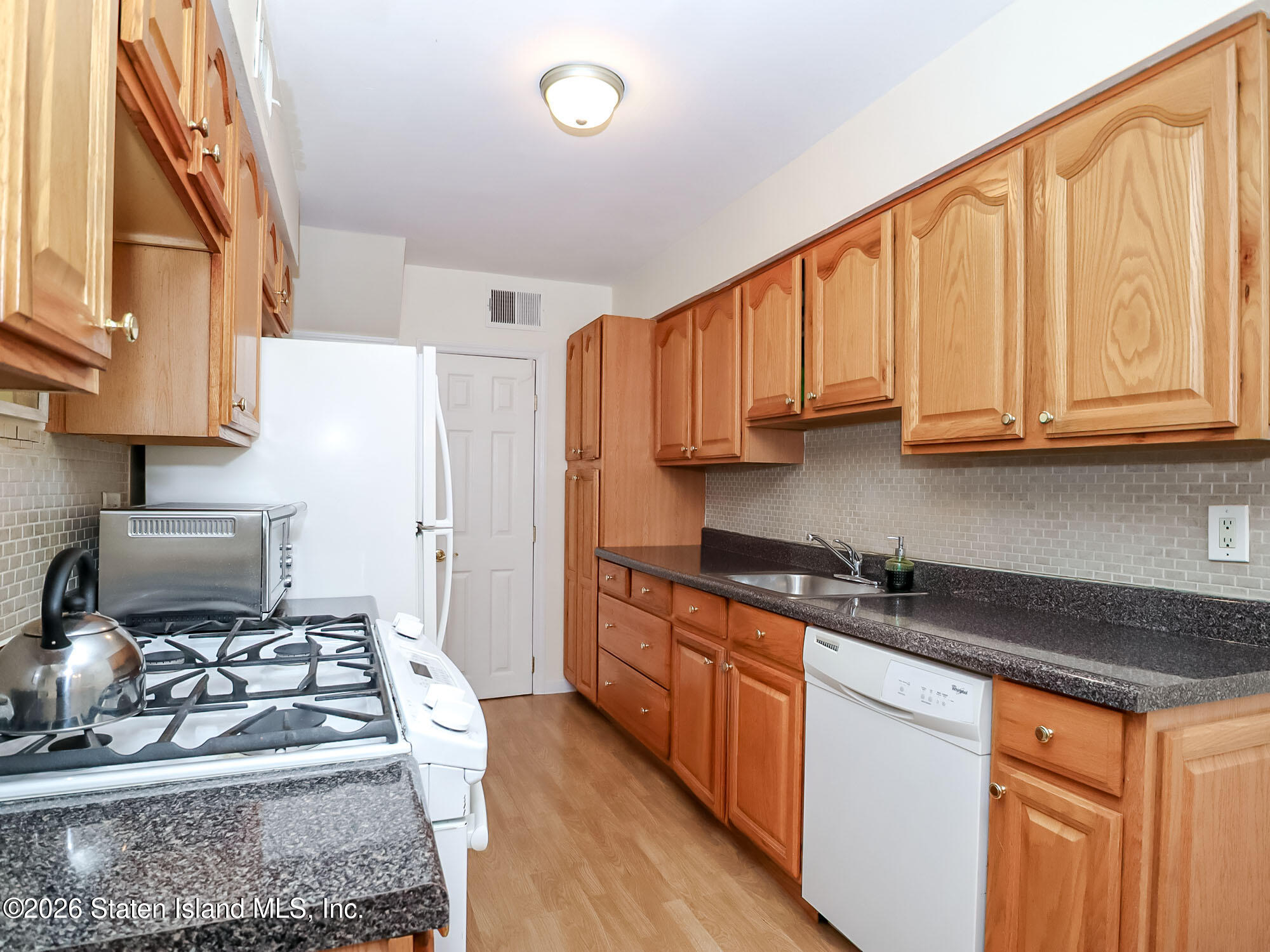 537 Willow Road East, Unit 1 Staten Island, NY 10314 - Photo 7 of 23 a kitchen with stainless steel appliances granite countertop a stove a sink dishwasher and cabinets with wooden floor