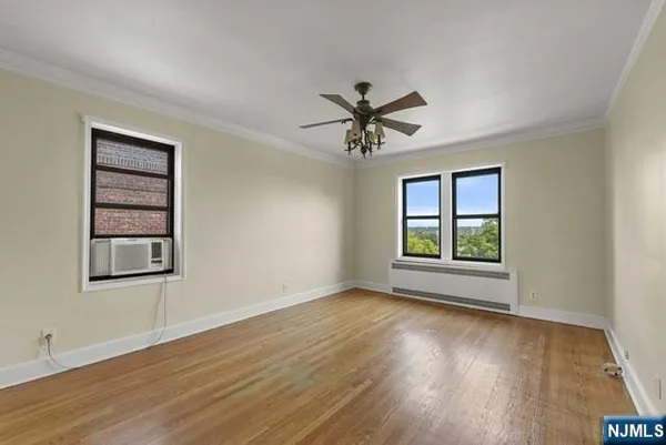 a view of an empty room with a window and wooden floor