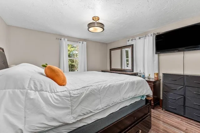 a bedroom with a bed and a flat tv screen on dresser