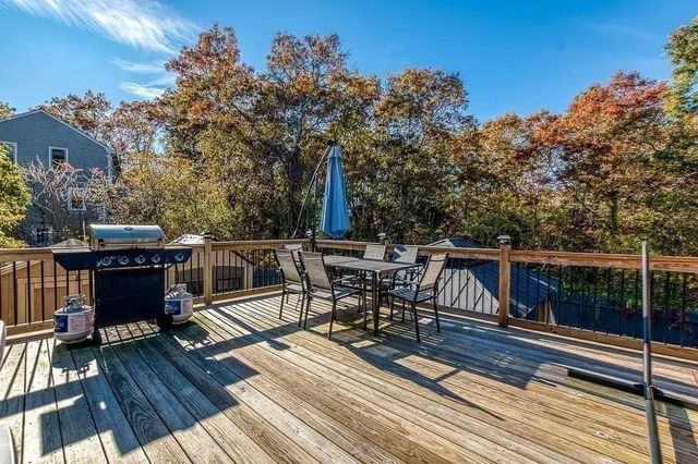 a view of a roof deck with table and chairs a barbeque with wooden floor and fence