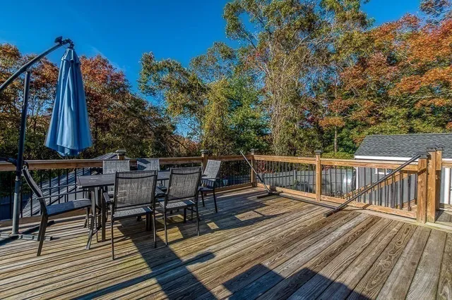 a view of a roof deck with table and chairs a barbeque with wooden floor and fence