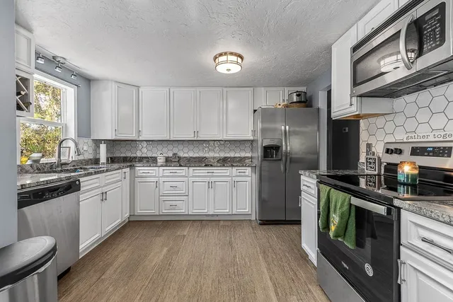 a kitchen with stainless steel appliances granite countertop a refrigerator a stove top oven a sink and dishwasher