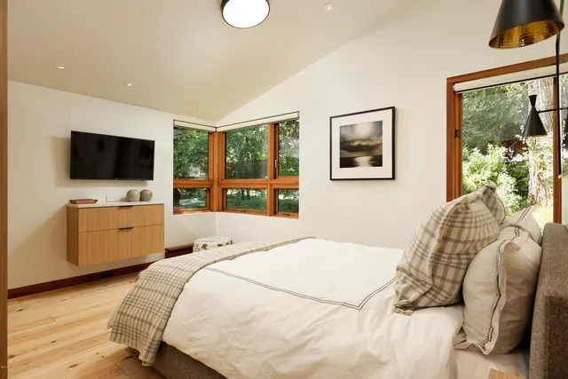 a bedroom with a bed and a flat tv screen on dresser