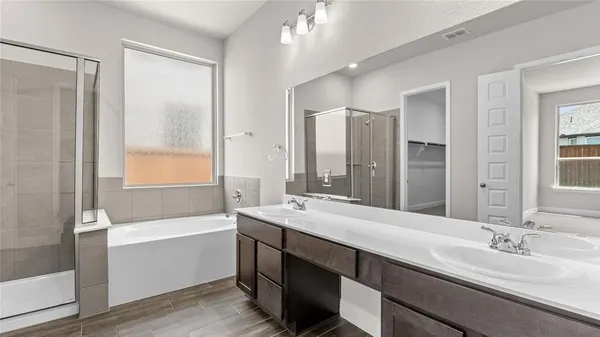 a bathroom with a sink double vanity granite tub shower and a mirror