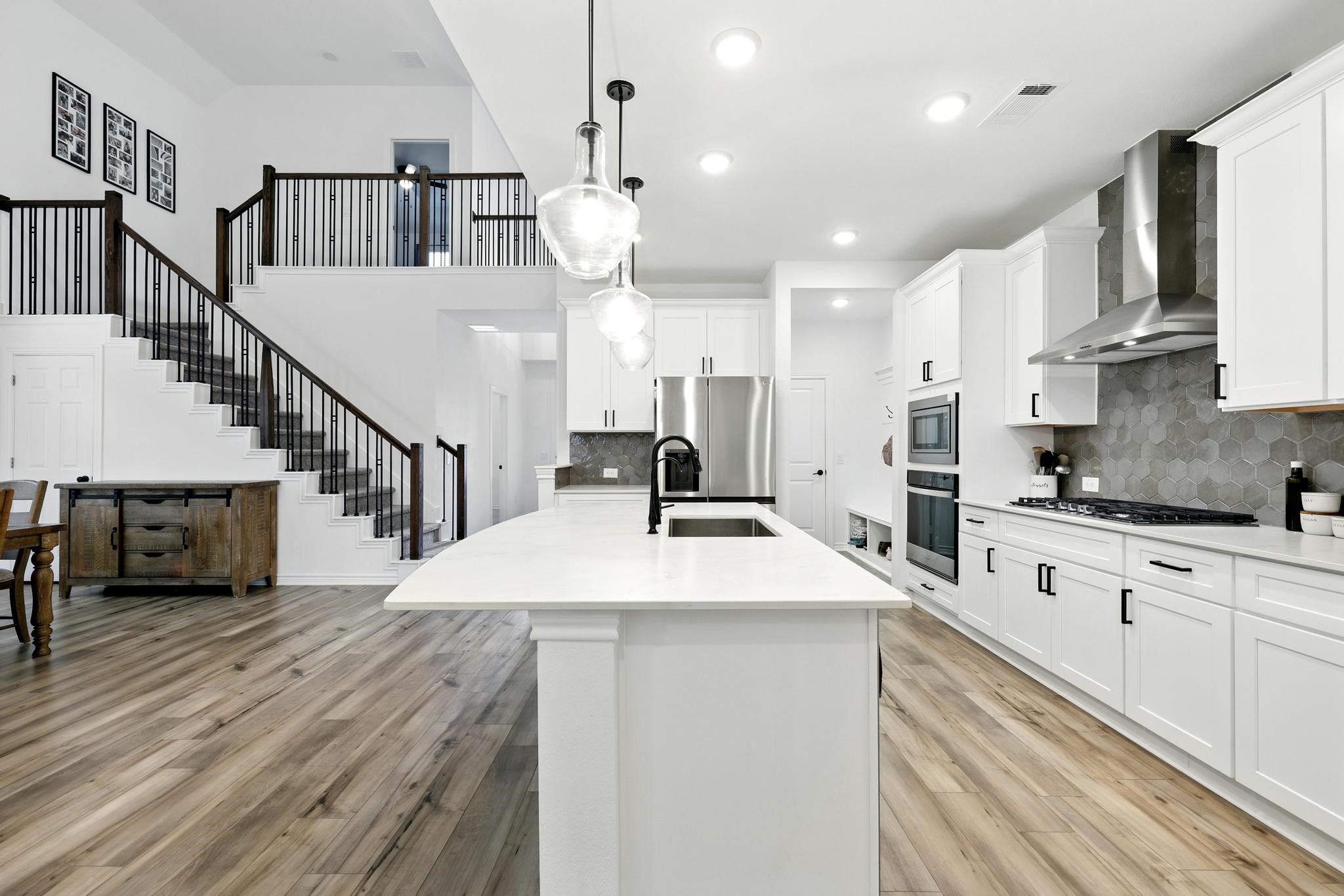 15727 Rosemary Hl Lane Conroe, TX 77302 - Photo 12 of 28 a room with stainless steel appliances kitchen island granite countertop a sink dishwasher a stove and a dining table with wooden floor