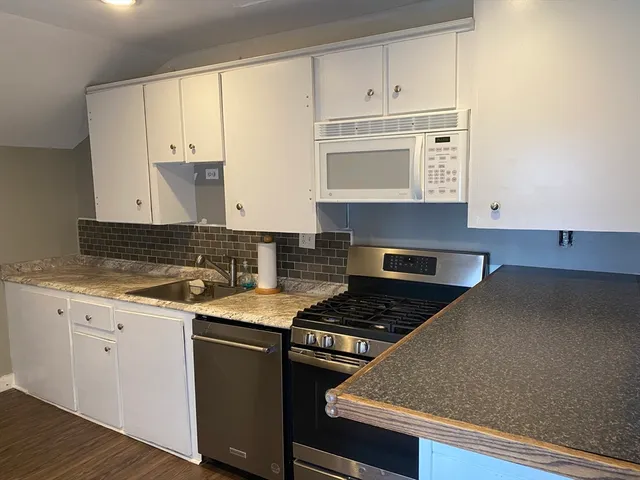 a kitchen with granite countertop a stove a sink and a refrigerator
