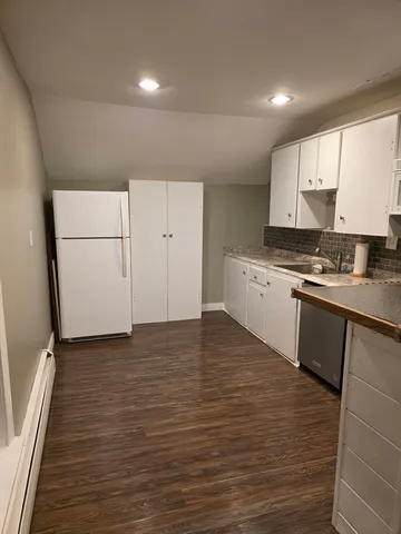 a view of a kitchen with wooden floor and electronic appliances