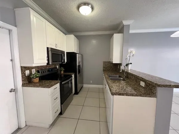 a kitchen with a sink a microwave a refrigerator and cabinets