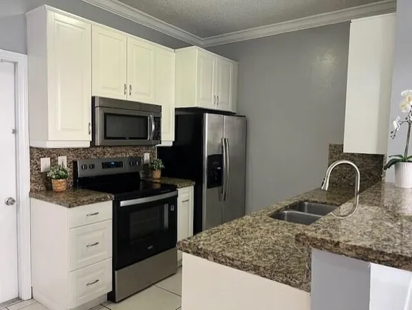 a kitchen with granite countertop a sink stainless steel appliances and white cabinets