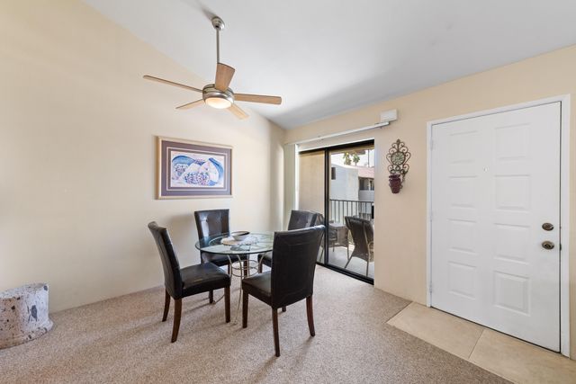 a dining room with furniture and a chandelier fan
