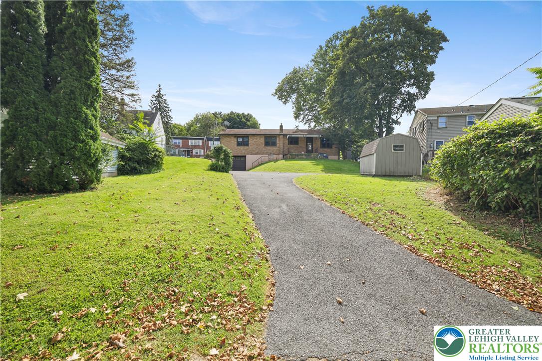 1539 Spring Garden Street Wilson, PA 18042 - Photo 30 of 34 An asphalt driveway leads to a classic brick home situated on a spacious grassy lot.