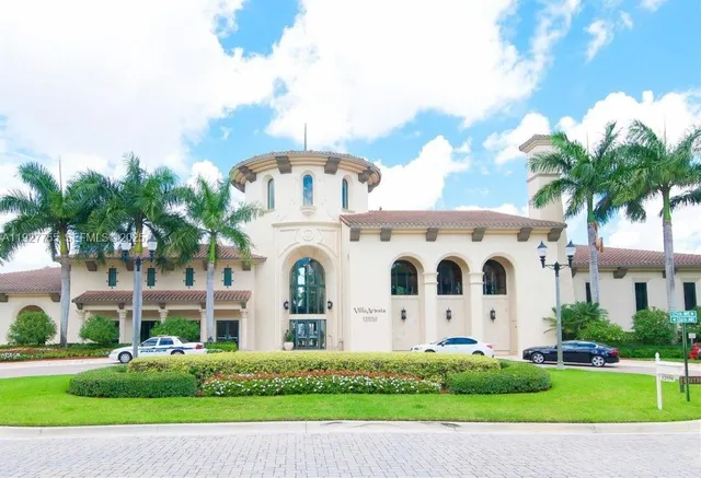 a view of a white building among the street with palm trees