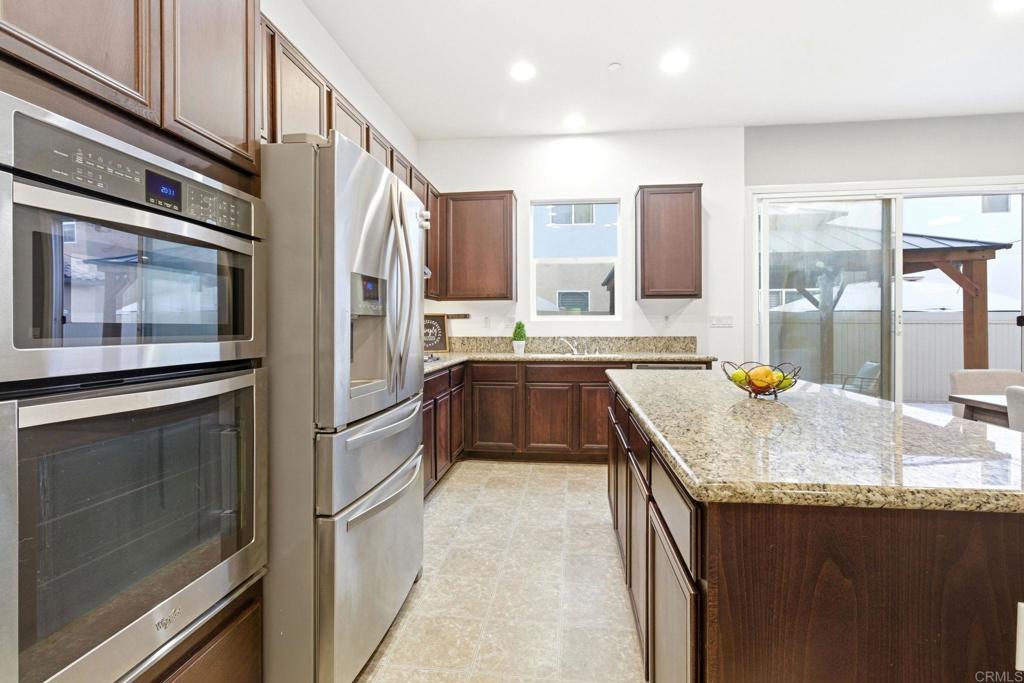 1508 Carpinteria Street Chula Vista, CA 91913 - Photo 10 of 39 a kitchen with stainless steel appliances granite countertop a refrigerator a stove and a sink with wooden cabinets
