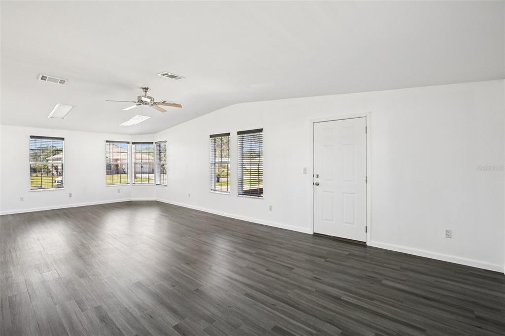 12373 Tree Street Largo, FL 33773 - Photo 18 of 43 an empty room with wooden floor chandelier and windows