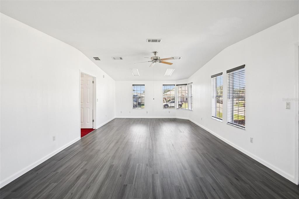 12373 Tree Street Largo, FL 33773 - Photo 19 of 43 an empty room with wooden floor chandelier fan and windows
