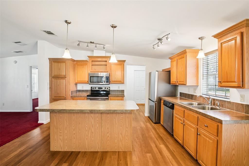 12373 Tree Street Largo, FL 33773 - Photo 9 of 43 a large kitchen with kitchen island a large counter space a sink appliances and cabinets