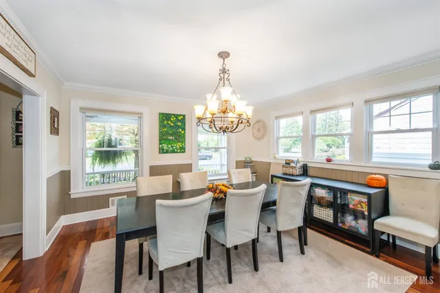 a dining room with wooden floor a chandelier a wooden table and chairs