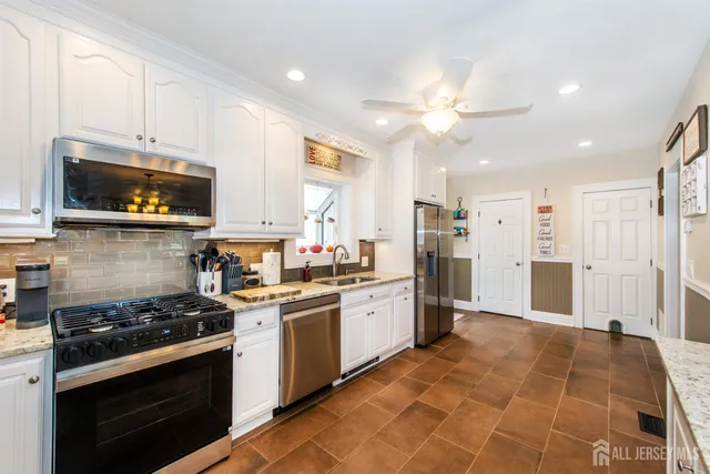 a kitchen with stainless steel appliances a stove a sink cabinets and a window