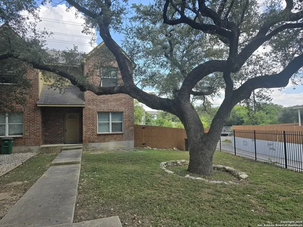 a front view of a house with a yard and a large tree