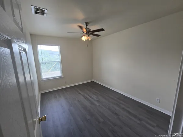 an empty room with wooden floor fan and windows