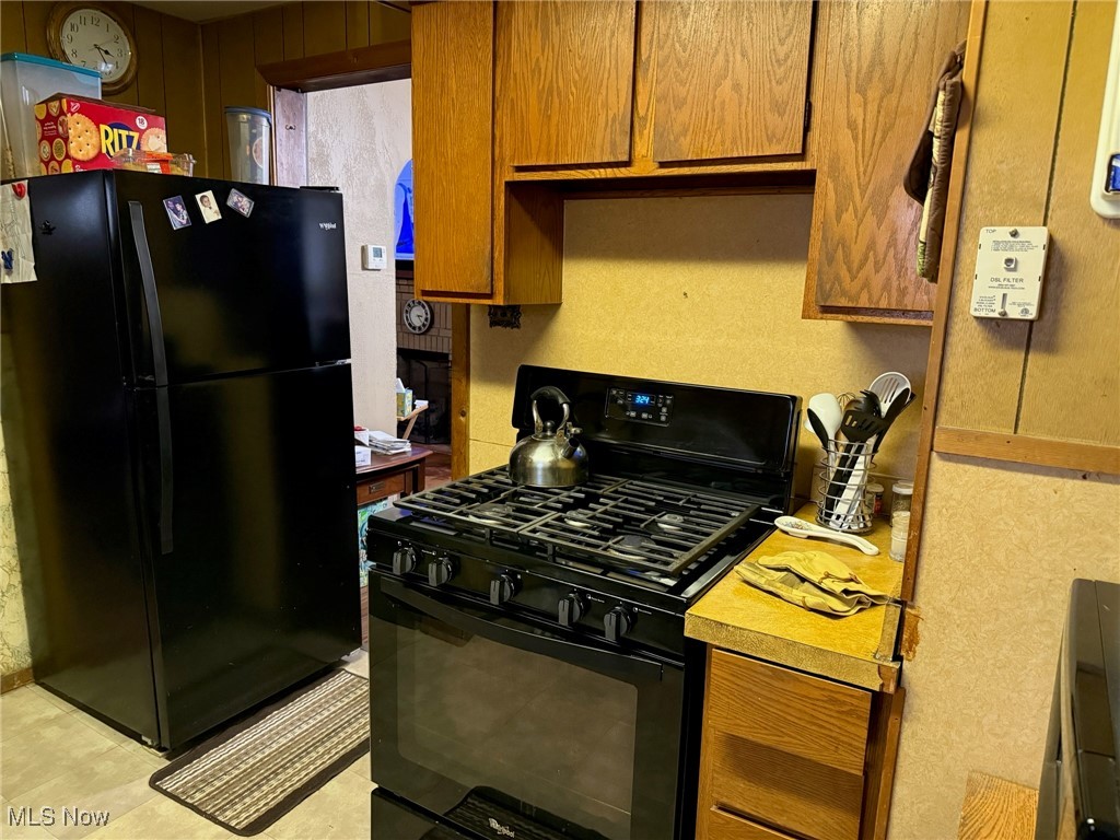 1311 Warner Road Southeast Canton, OH 44707 - Photo 4 of 14 Kitchen featuring black appliances, brown cabinetry, and light countertops