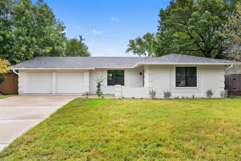 7507 Daugherty Street Austin, TX 78757 - Photo 1 of 25 White brick exterior featuring a dark asphalt shingle roof, two-car garage, and dark-framed windows