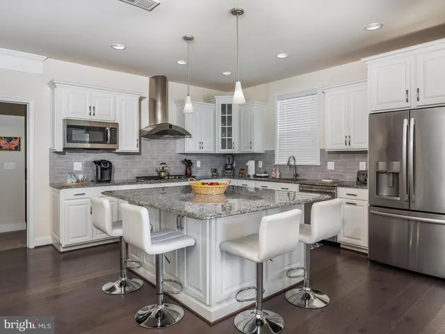 a kitchen with stainless steel appliances granite countertop a stove top oven a sink dishwasher a dining table and chairs with wooden floor