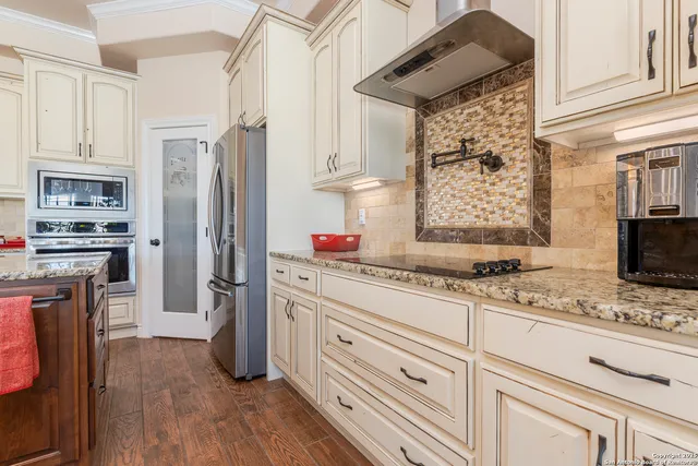 a kitchen with stainless steel appliances granite countertop a refrigerator oven stove a sink dishwasher and white cabinets with wooden floor