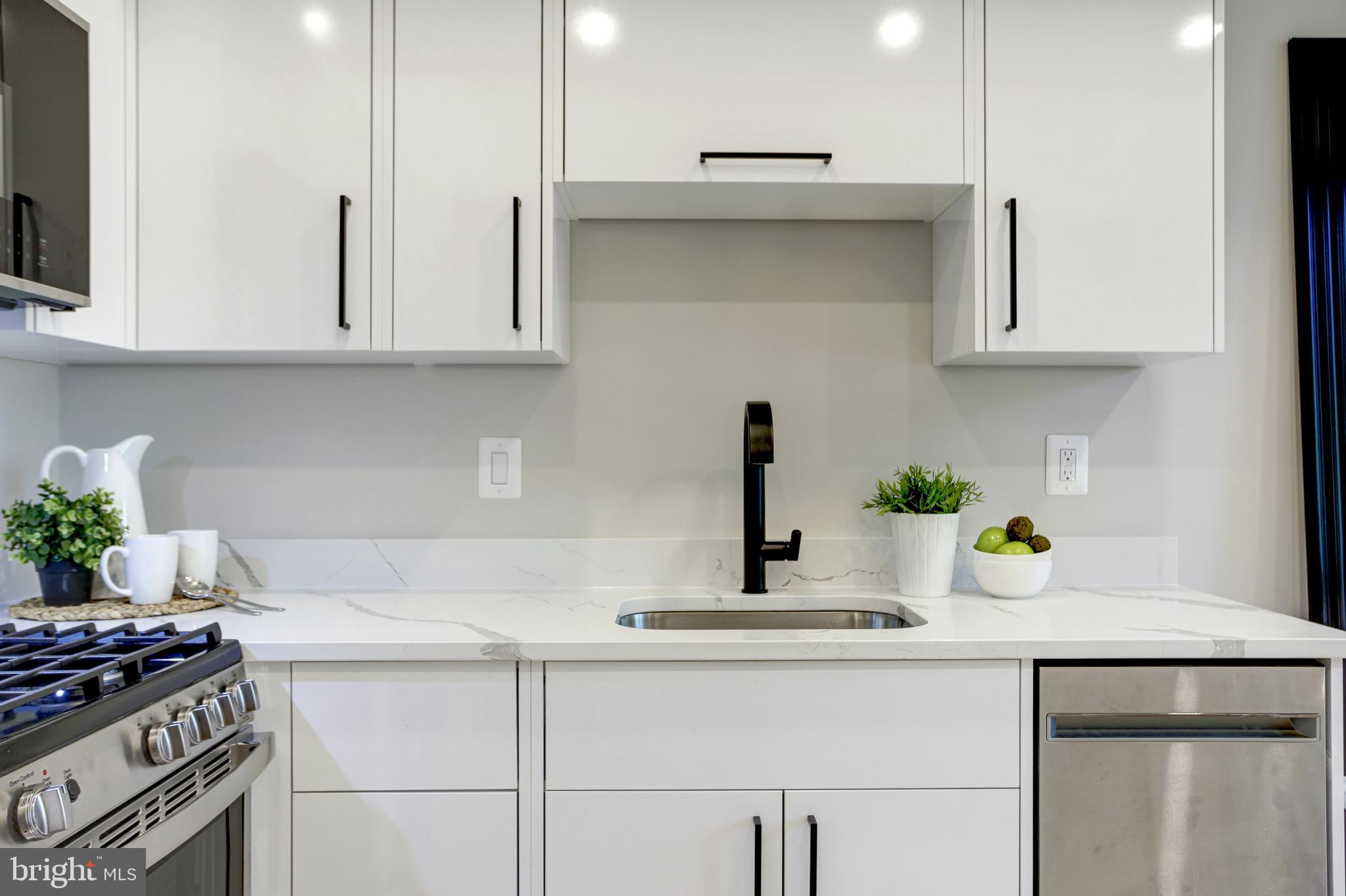 2301 Ontario Road Northwest, Unit 101 Washington, DC 20009 - Photo 6 of 24 a kitchen with stainless steel appliances a sink a stove and white cabinets